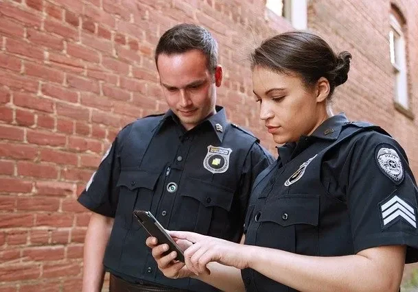 Two police officers looking at a cell phone.